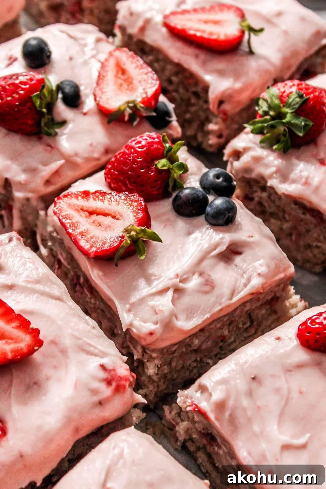 sliced strawberry sheet cake on parchment lined wire rack decorated with fresh strawberries and blueberries (4)