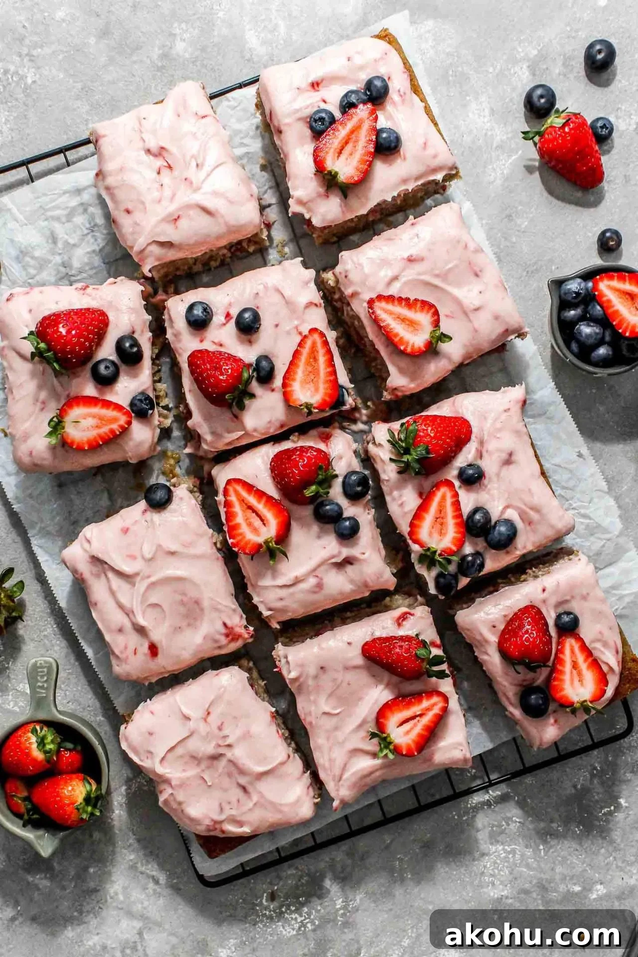 sliced strawberry sheet cake on parchment lined wire rack decorated with fresh strawberries and blueberries (3)