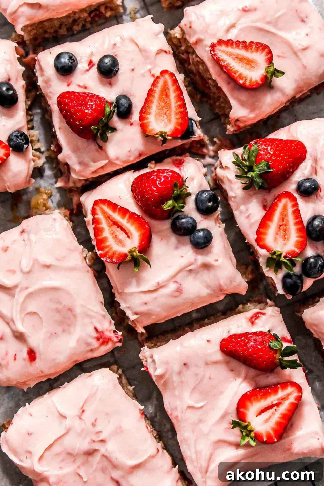 sliced strawberry sheet cake on parchment lined wire rack decorated with fresh strawberries and blueberries (2)