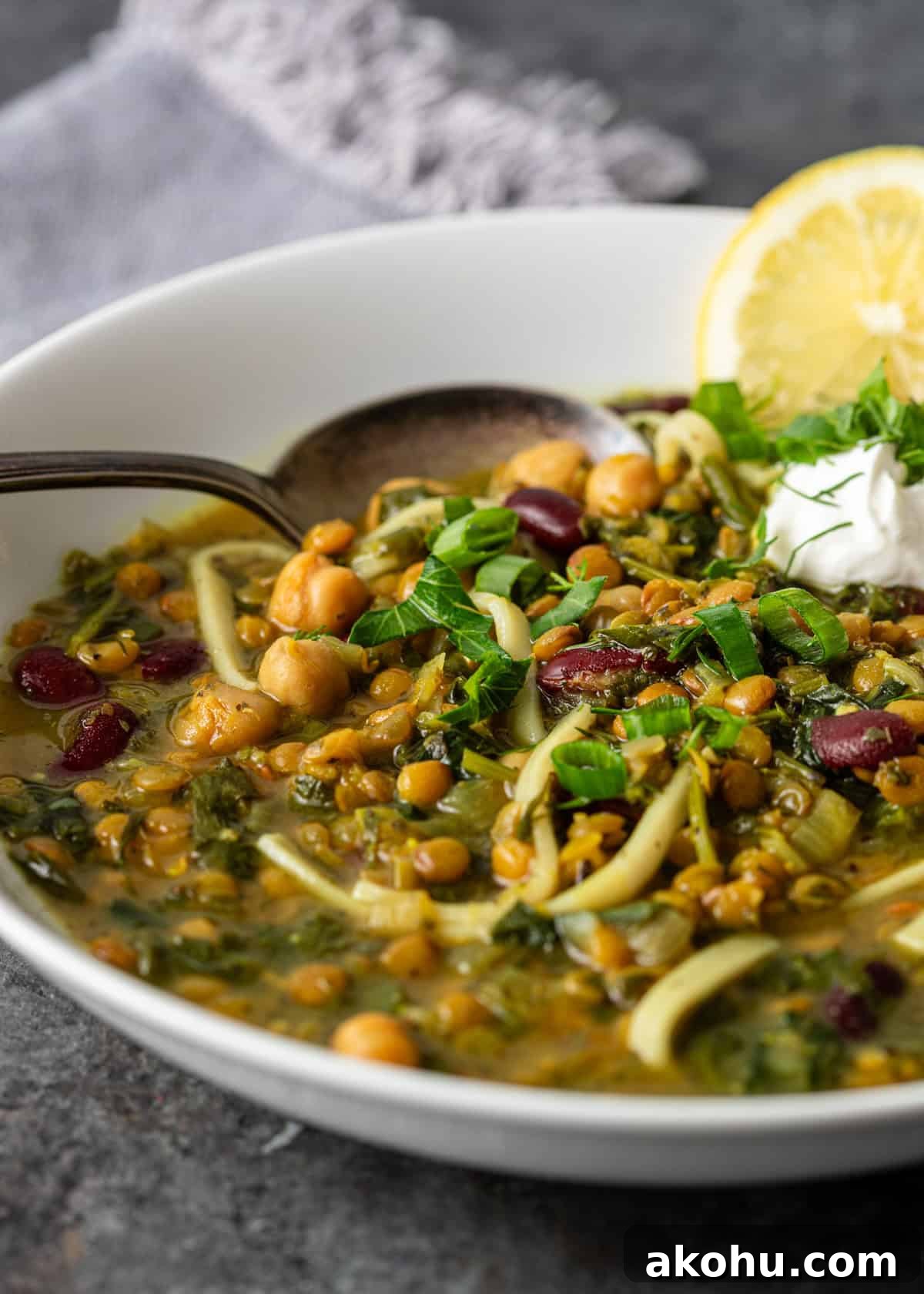 side view closeup: a bowl of my ash reshteh recipe with fresh herbs on top