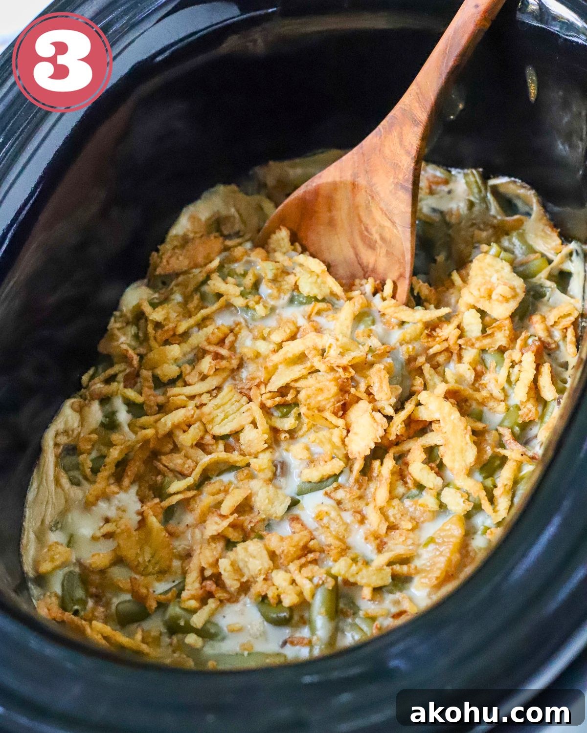 A slow cooked green bean casserole with a spoon in it.
