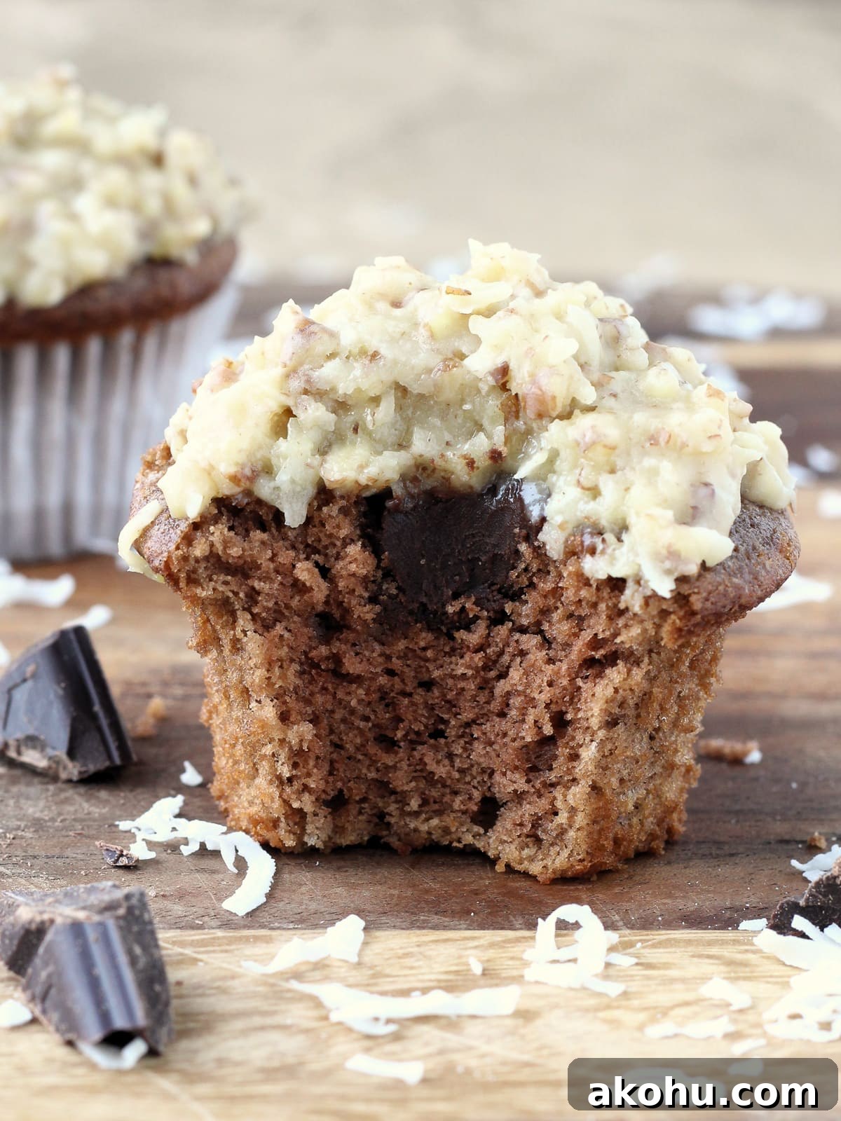 Decadent German Chocolate Cupcakes with Coconut-Pecan Frosting 2 Bitten German chocolate cupcake showing moist crumb and creamy ganache.