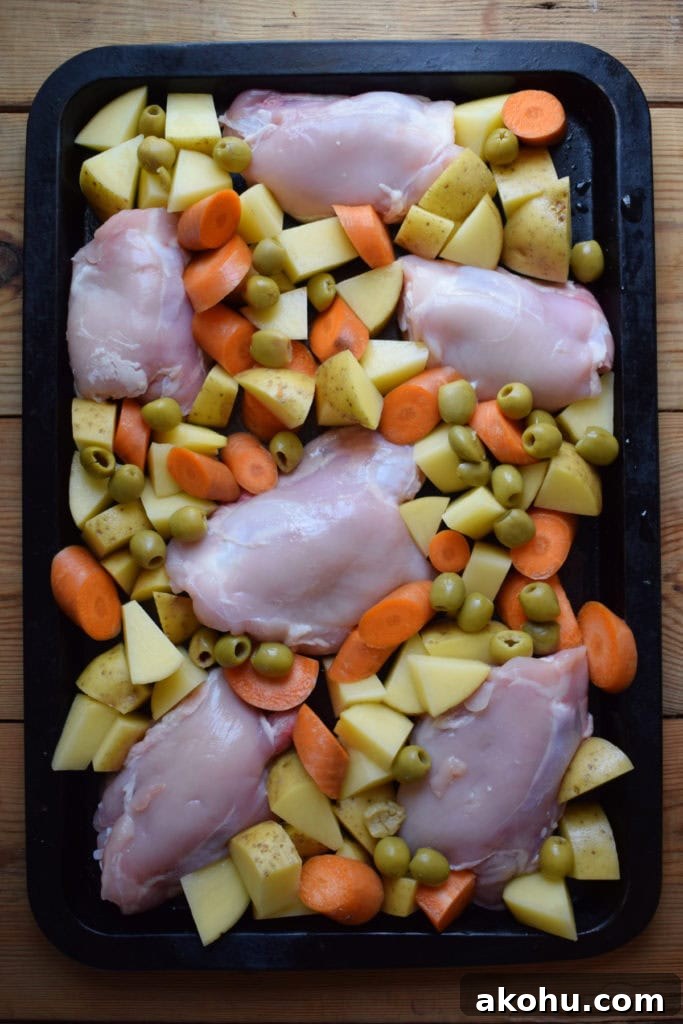 Chicken, vegetables and olives on a baking tray.