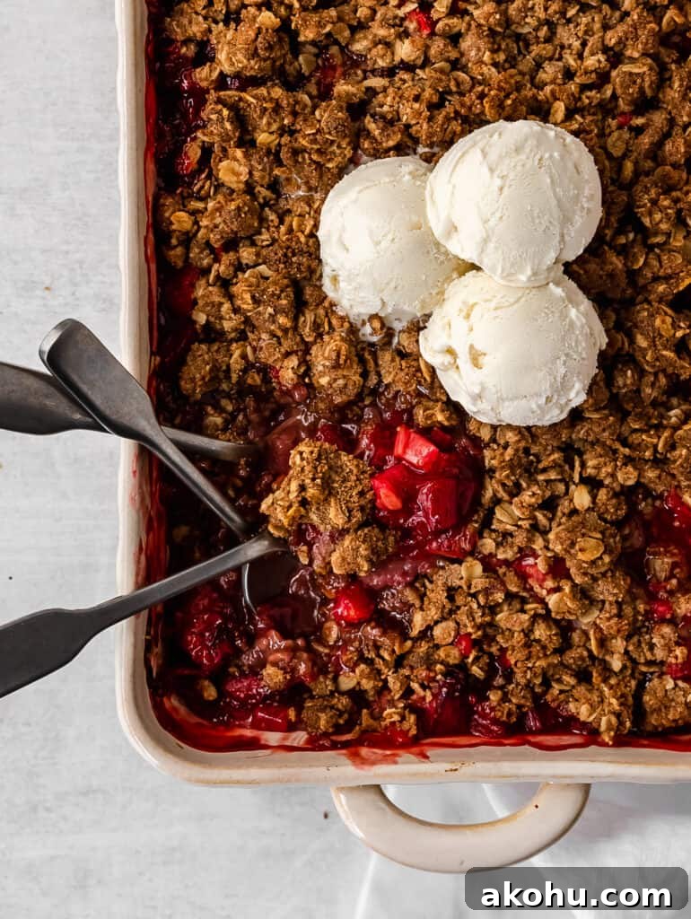 close up of strawberry rhubarb crisp with melting ice cream 