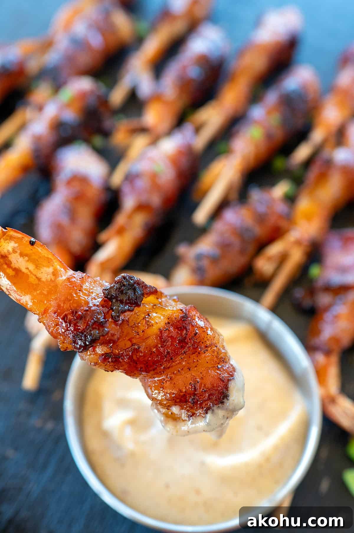 Dipping bacon-wrapped shrimp in aioli.
