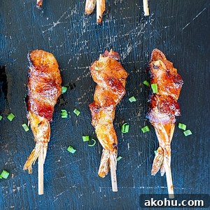 3 skewered bacon-wrapped shrimp on a platter.