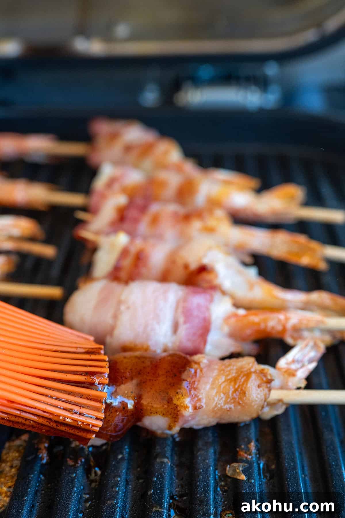 Brushing bacon-wrapped shrimp with glaze.
