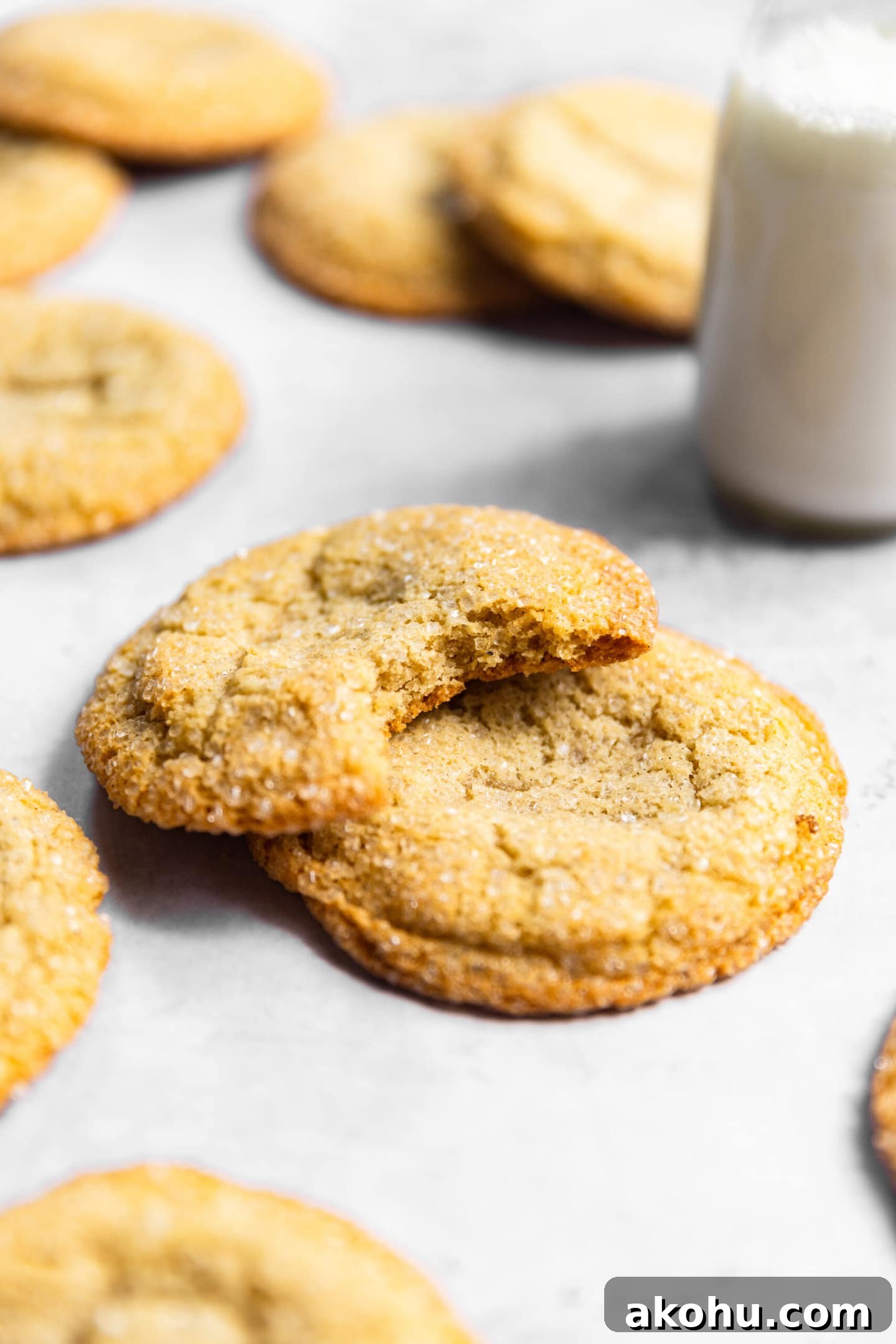 Drop-Style Vanilla Sugar Cookies: Quick Classic Recipe 2 Sugar cookies stacked on top of each other with a bite missing from one next to a glass of milk.