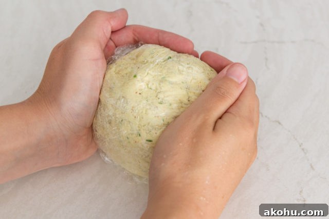 Everything Bagel Cheese Ball Recipe for Parties and Snacks 9 Fully Shaped Ball of Cheese with hands Cupping It