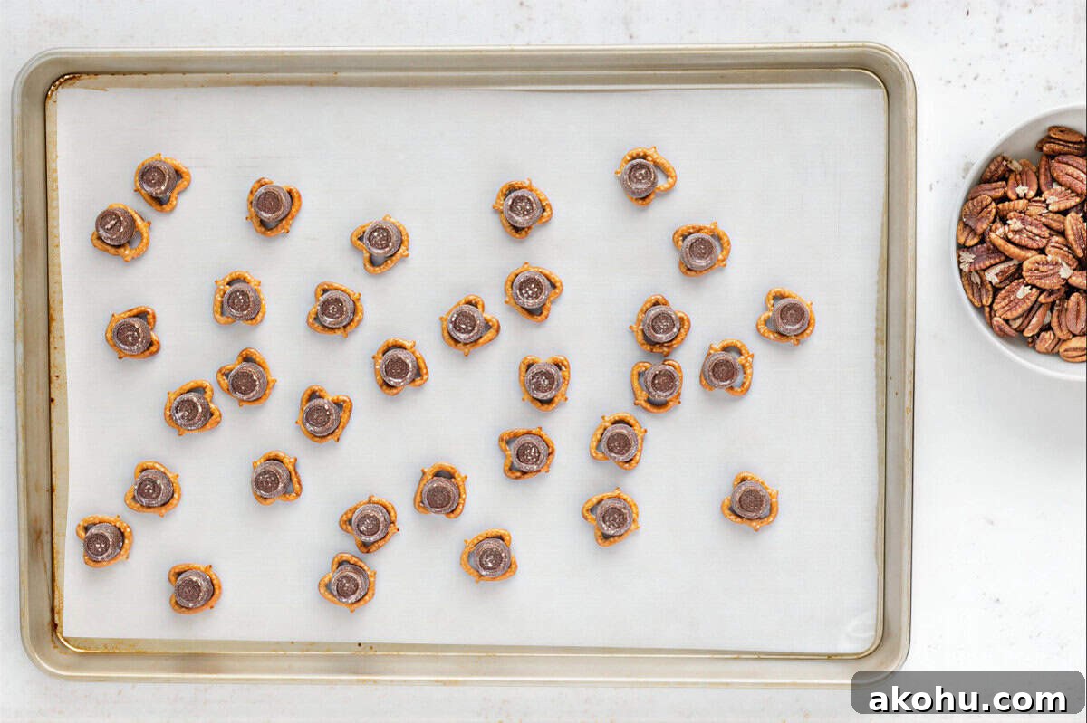 pretzels topped with rolos on a lined baking sheet.