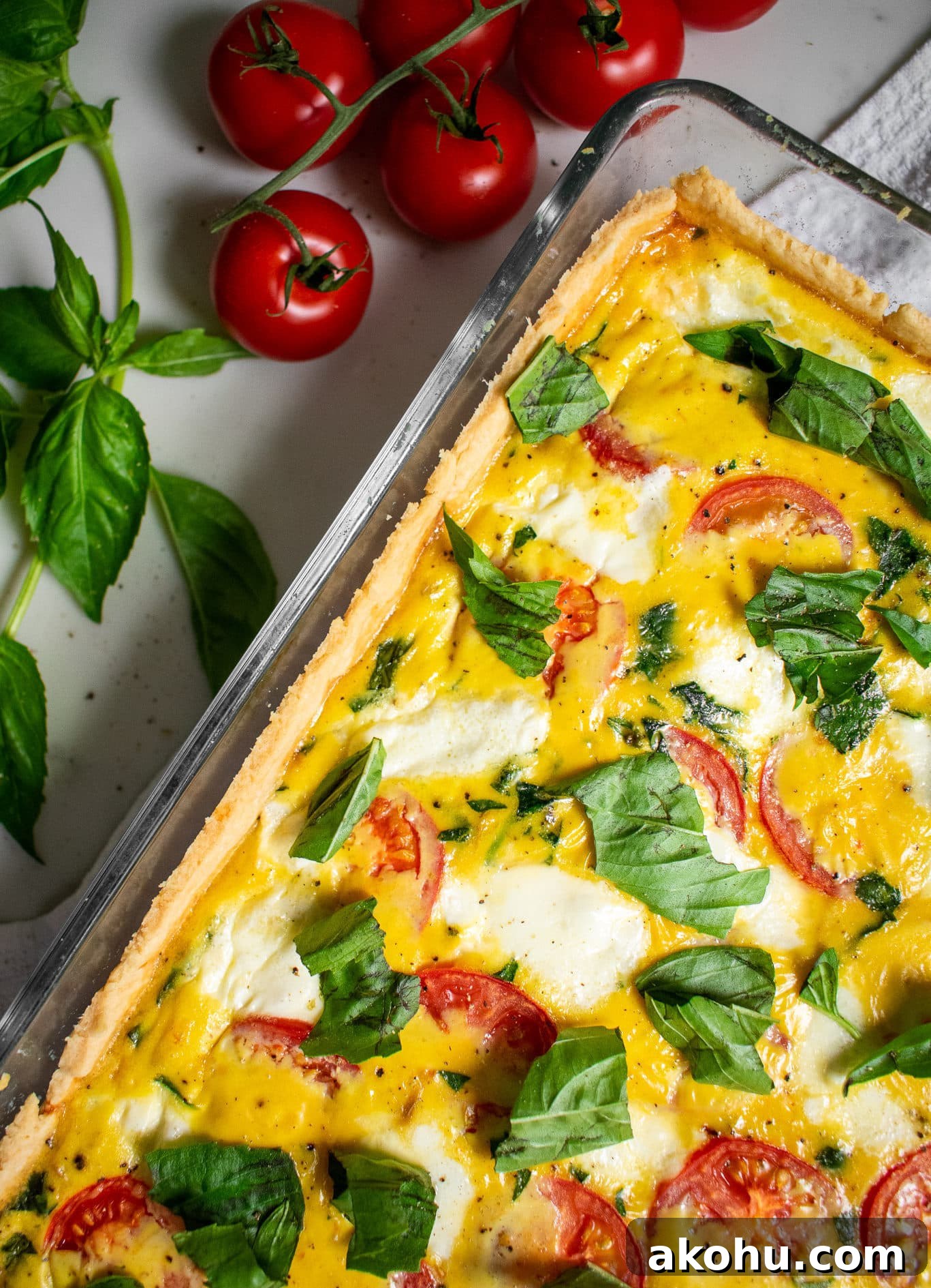 A quiche with basil, mozzarella, and tomato.