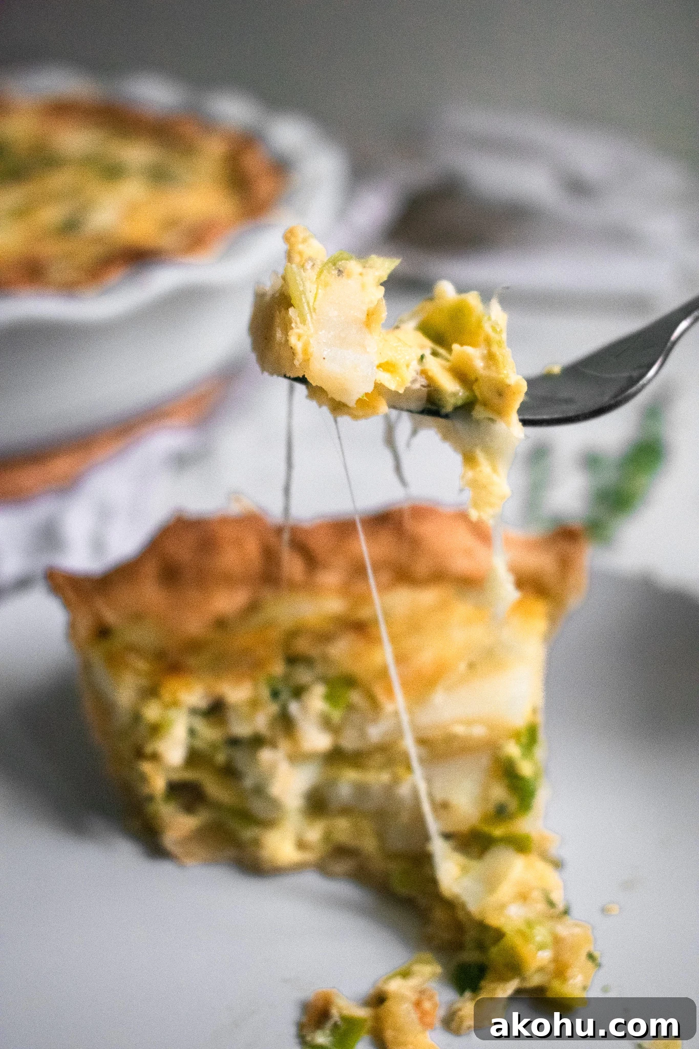A cheese pull from a piece of quiche with potatoes and leeks