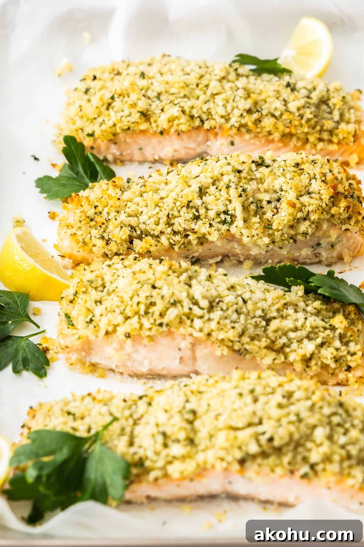 Easter Dinner Mains: Elegant Roast and Ham Recipes 13 Baking tray with cooked Herb Panko Salmon, garnished with some parsley leaves and lemon wedges.