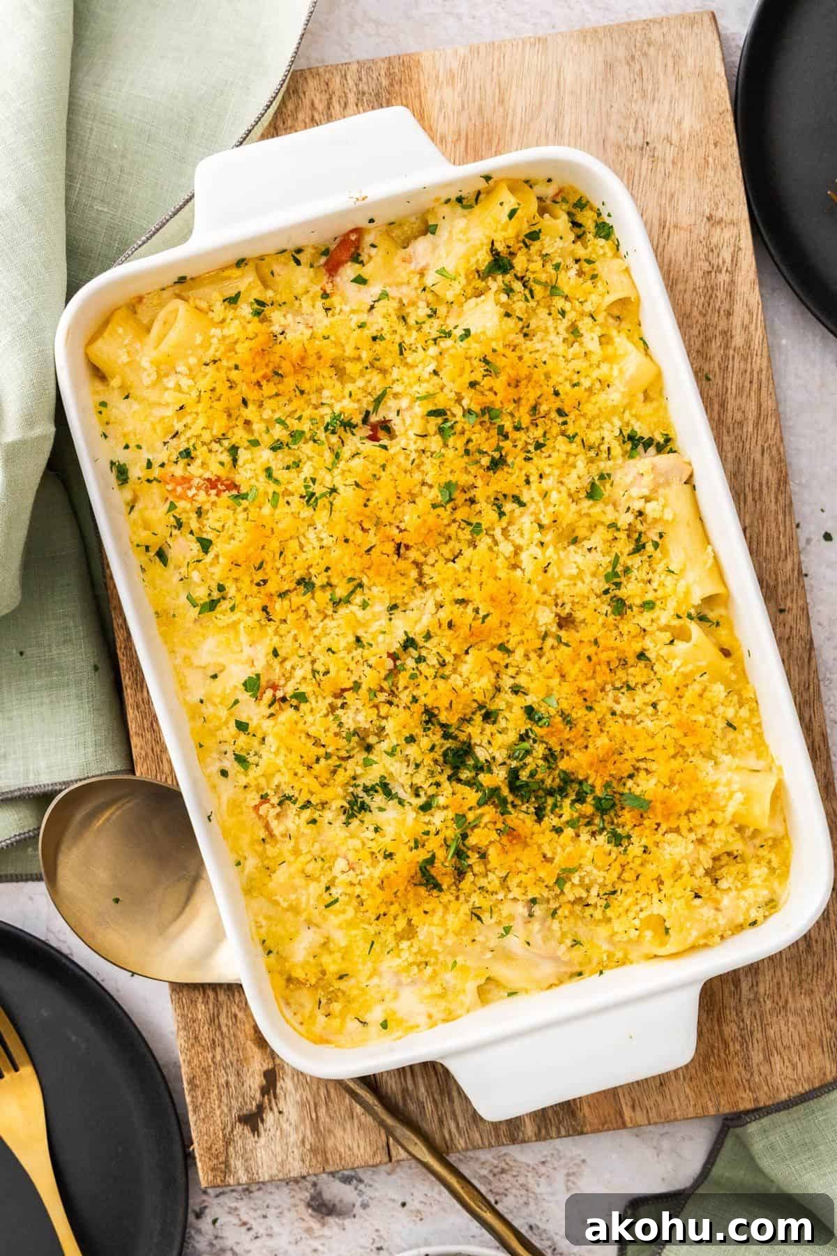 Easter Dinner Mains: Elegant Roast and Ham Recipes 5 Large white rectangular dish of Creamy Tuna Pasta Bake, sitting on a wooden board, with a gold serving spoon on the edge.
