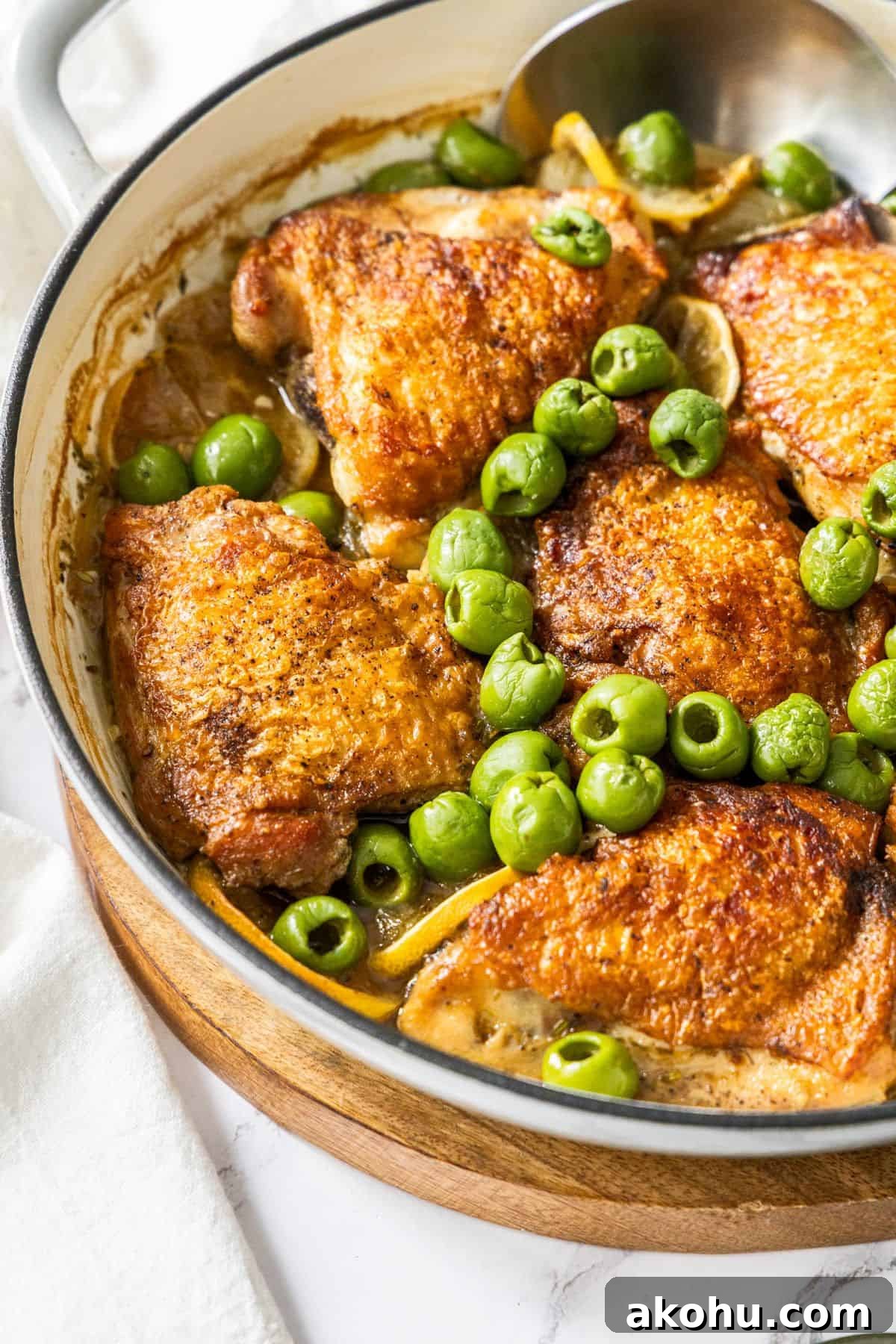 Easter Dinner Mains: Elegant Roast and Ham Recipes 6 Round dish with the Braised Chicken, Lemon and Olives, with a spoon resting in the dish.