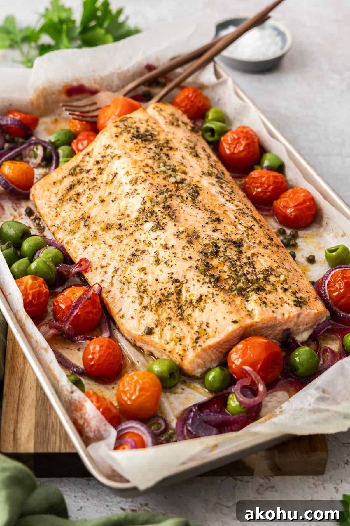 Easter Dinner Mains: Elegant Roast and Ham Recipes 7 Sheet pan with side of Mediterranean Salmon and vegetables around the edge, with serving utensils.