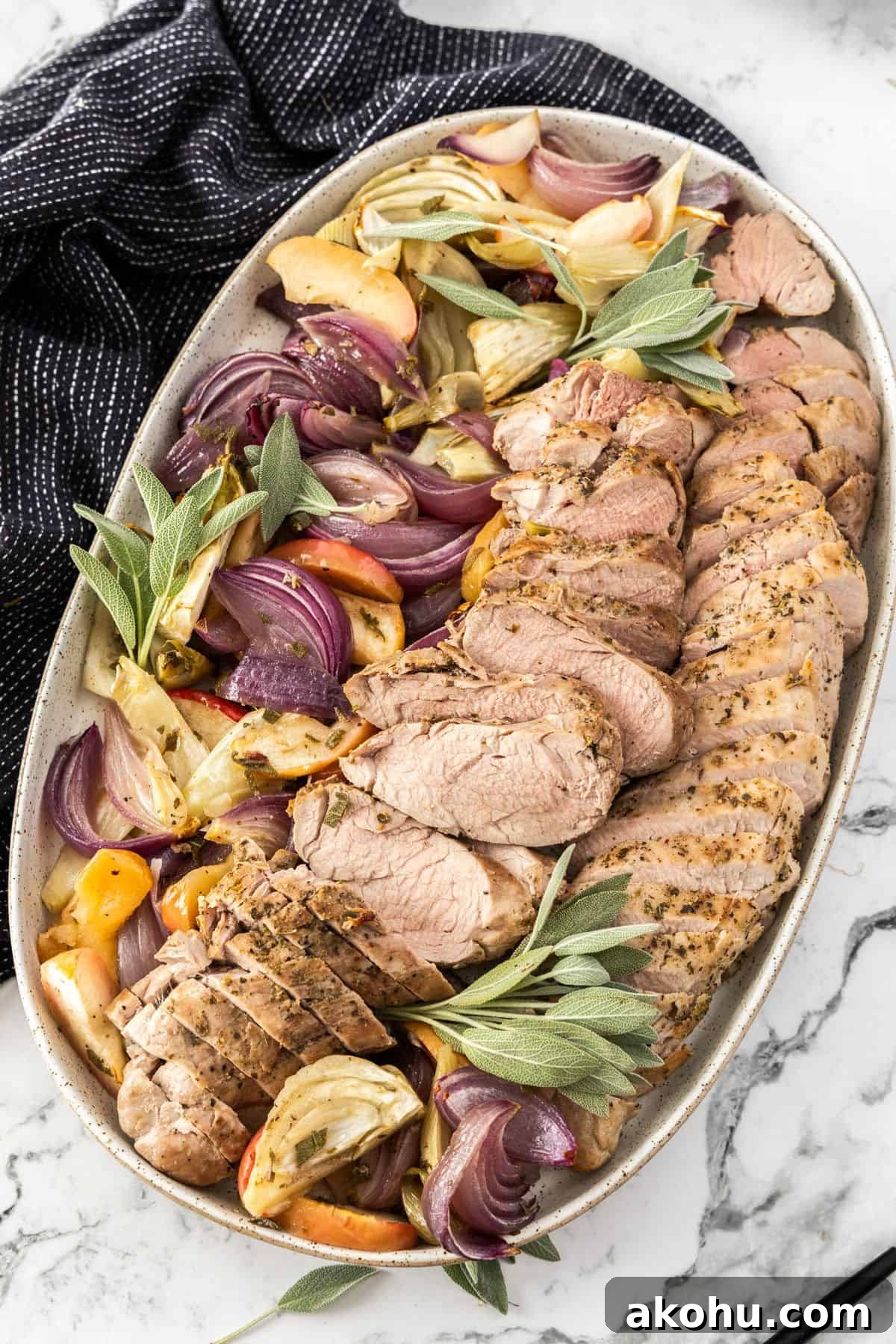 Easter Dinner Mains: Elegant Roast and Ham Recipes 8 Platter of sliced Roasted Pork Tenderloin, surrounded by pieces of apple, fennel, onion and sage, with a black towel on edge.
