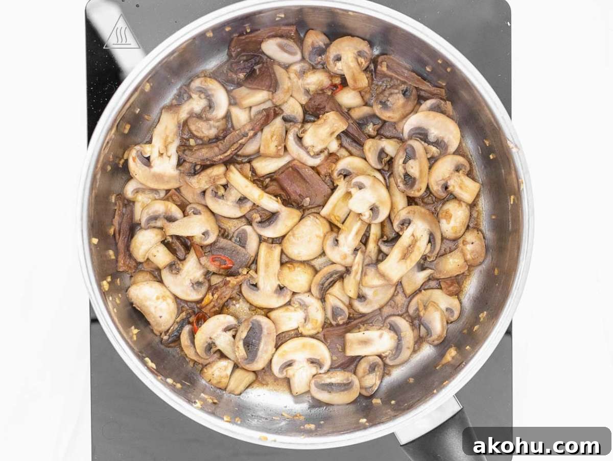 Step 1 Garlic ginger chili and mushrooms sautéing in pot for flavorful tofu soup base.