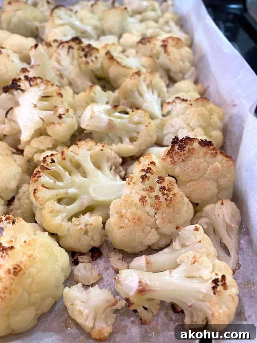Oven-roasted cauliflower on a baking pan lined with parchment paper.