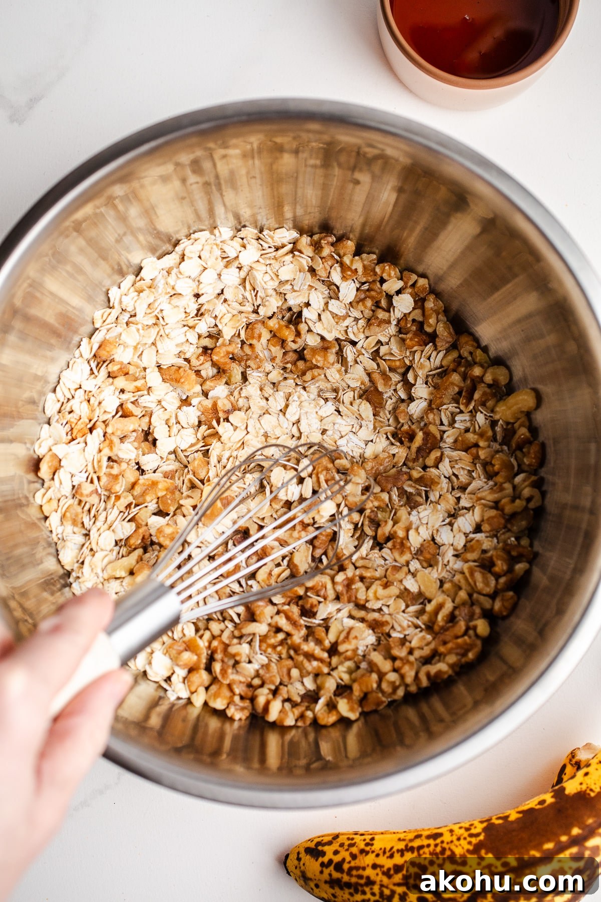 Banana Bread Granola Recipe: Crunchy, Cinnamon-Maple Cluster 5 Oats and walnuts in a mixing bowl.