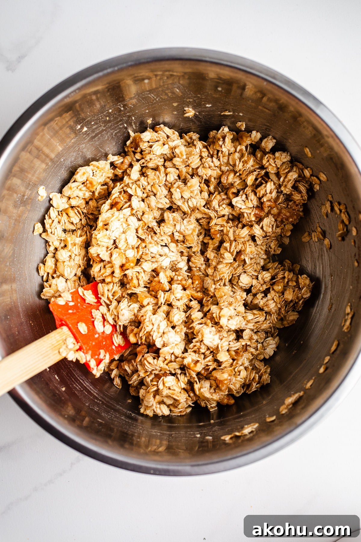 Banana Bread Granola Recipe: Crunchy, Cinnamon-Maple Cluster 7 Coated oats and walnuts in a mixing bowl.