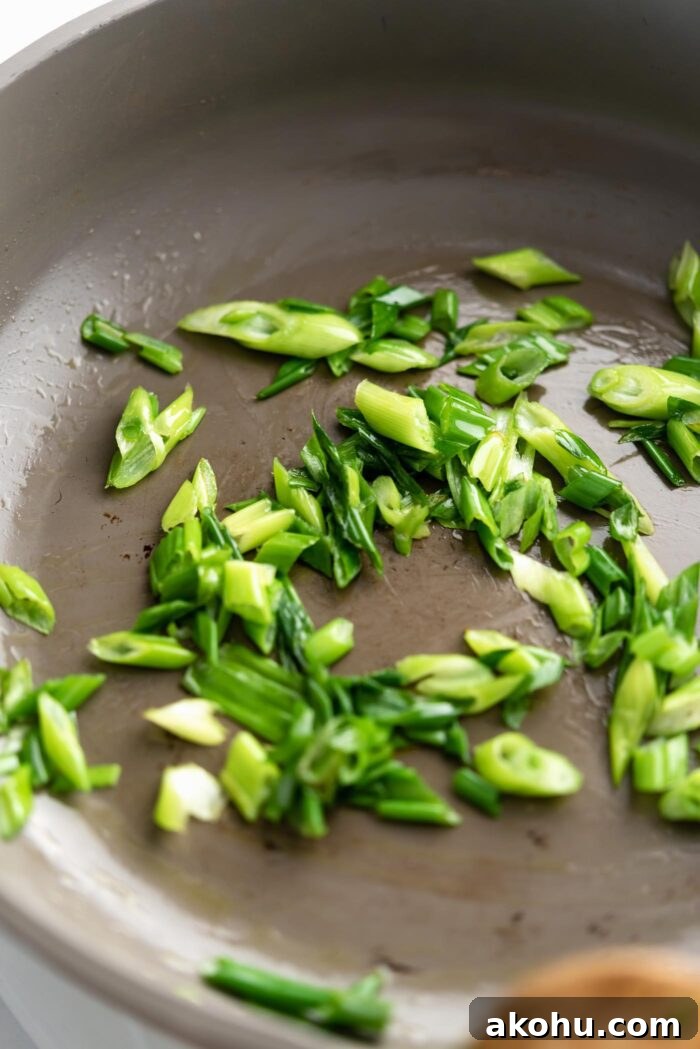 Thinly sliced stir fried green onions cooking in a pan.
