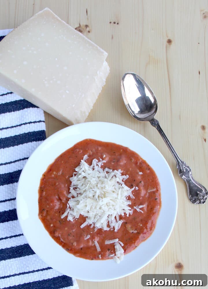Overhead photo of a bowl of tomato soup with a block of parmesan cheese.
