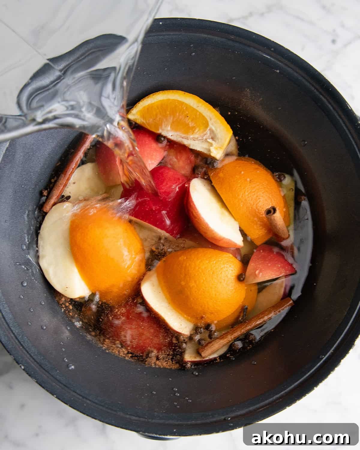how to make apple cider recipe - water being poured over the ingredients in the crock pot