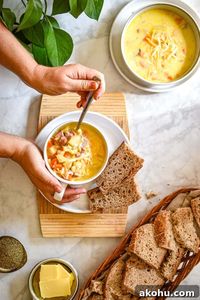 two hands are holding the Instant pot ham and potato soup and one is lifting the spoon