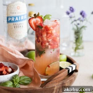 Closeup of a strawberry basil vodka cocktail on a wooden tray.