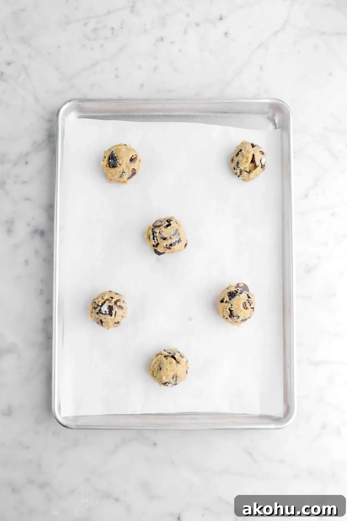 Oreo Stuffed Chocolate Chip Cookies: Gooey, Crunchy Dessert 8 six balls of cookie dough on lined parchment paper.