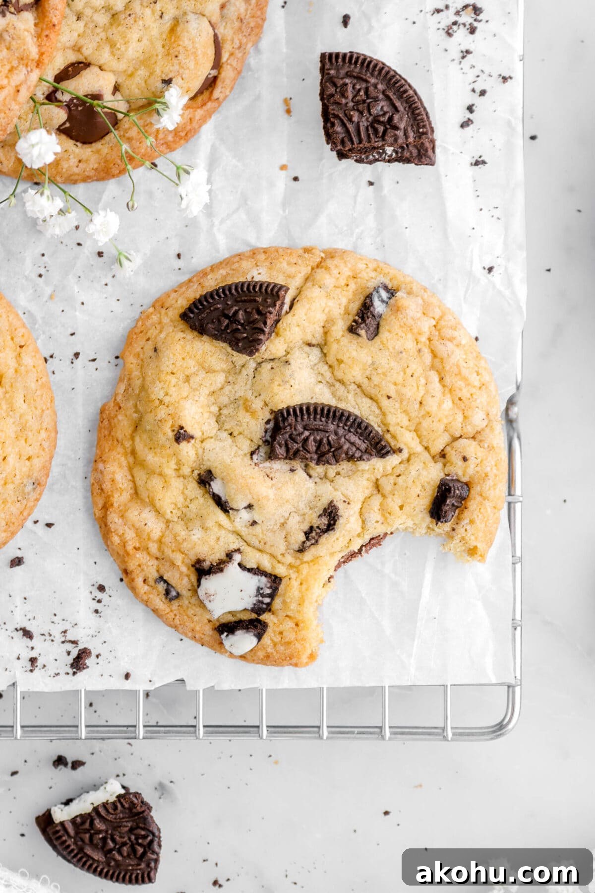 Oreo Stuffed Chocolate Chip Cookies: Gooey, Crunchy Dessert 3 close up overhead shot of oreo cookie with bite missing on parchment paper on cooling rack.