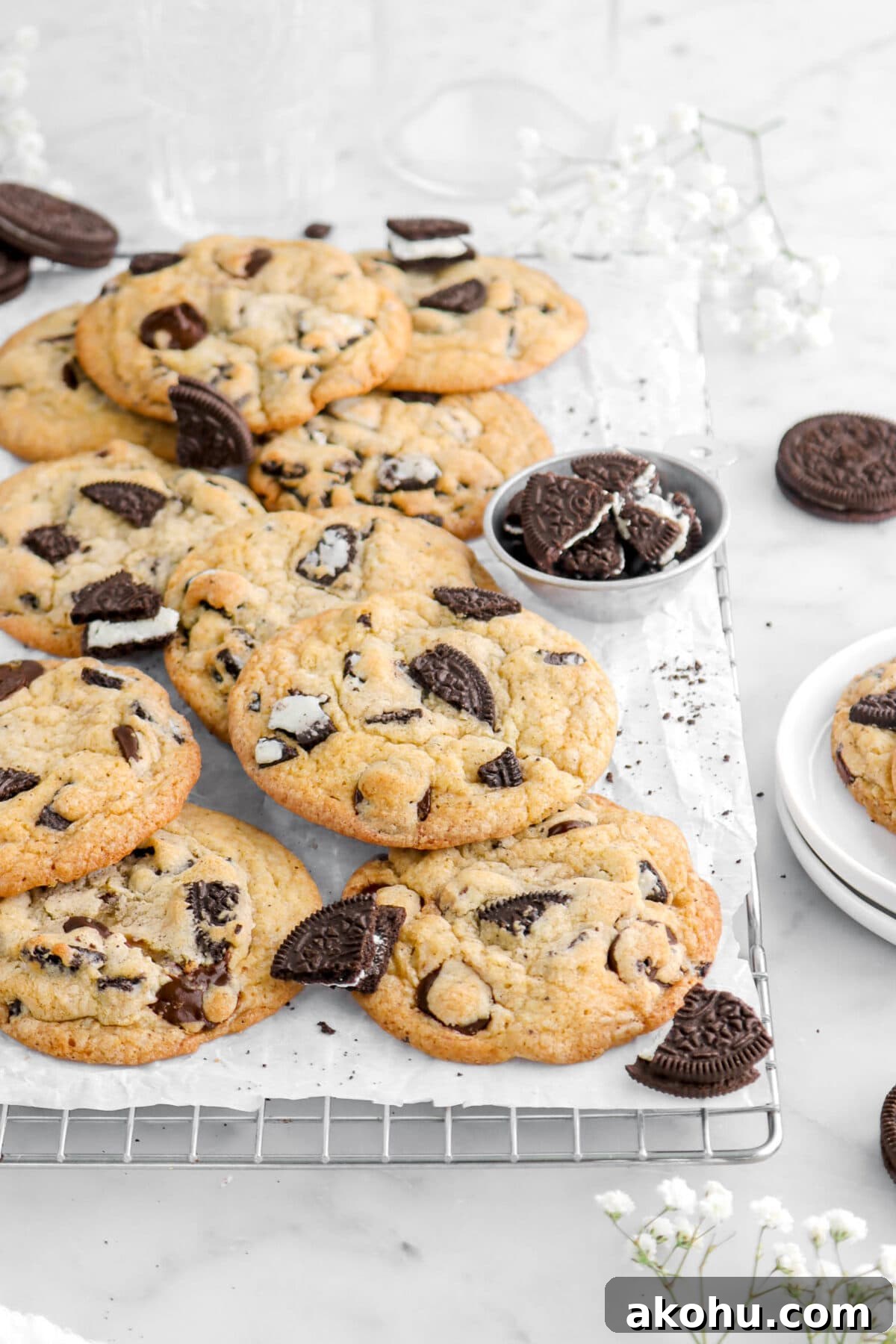 Oreo Stuffed Chocolate Chip Cookies: Gooey, Crunchy Dessert 4 angled cropped shot of cookies with oreos around on cooling rack lined with parchment paper with flowers around.