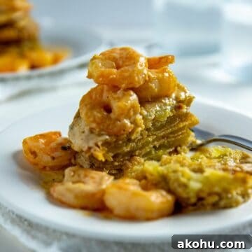 fried green tomatoes stacked on white plate with shrimp creole sauce poured on top