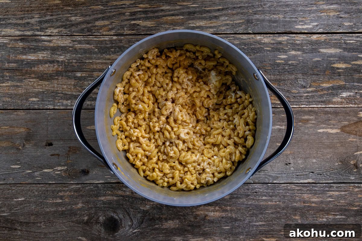 Cream cheese and cheddar cheese added to the cooked macaroni in the pot.