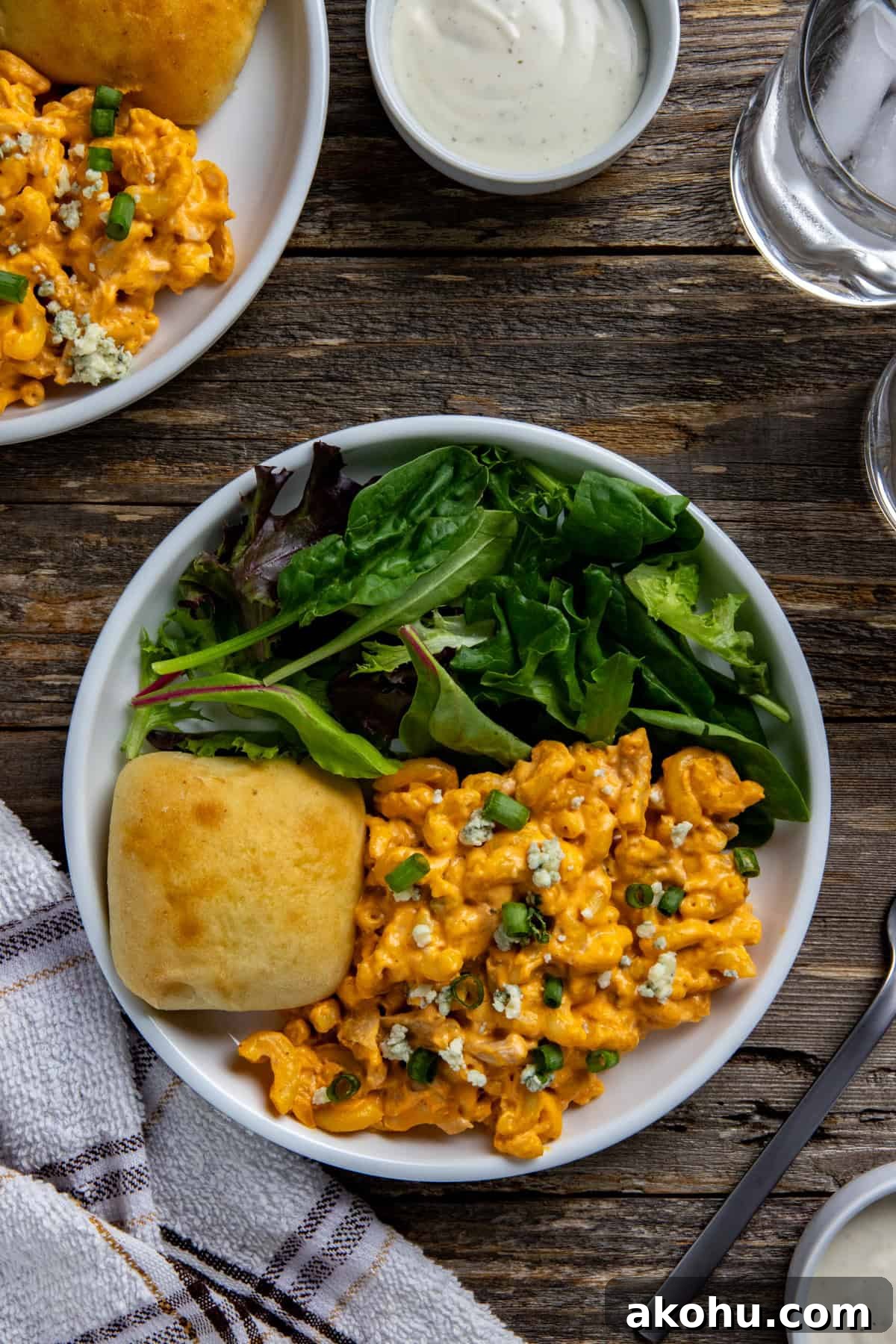 Cooked buffalo mac and cheese on a plate with a roll and simple salad.