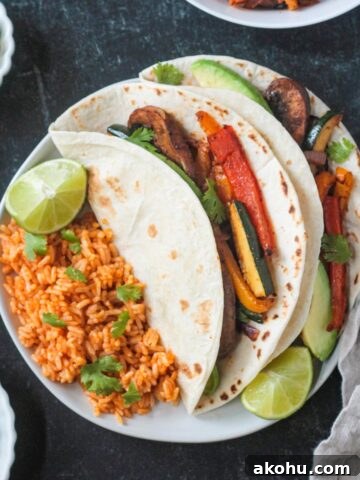 Two vegan fajitas on a plate with Spanish-style rice.