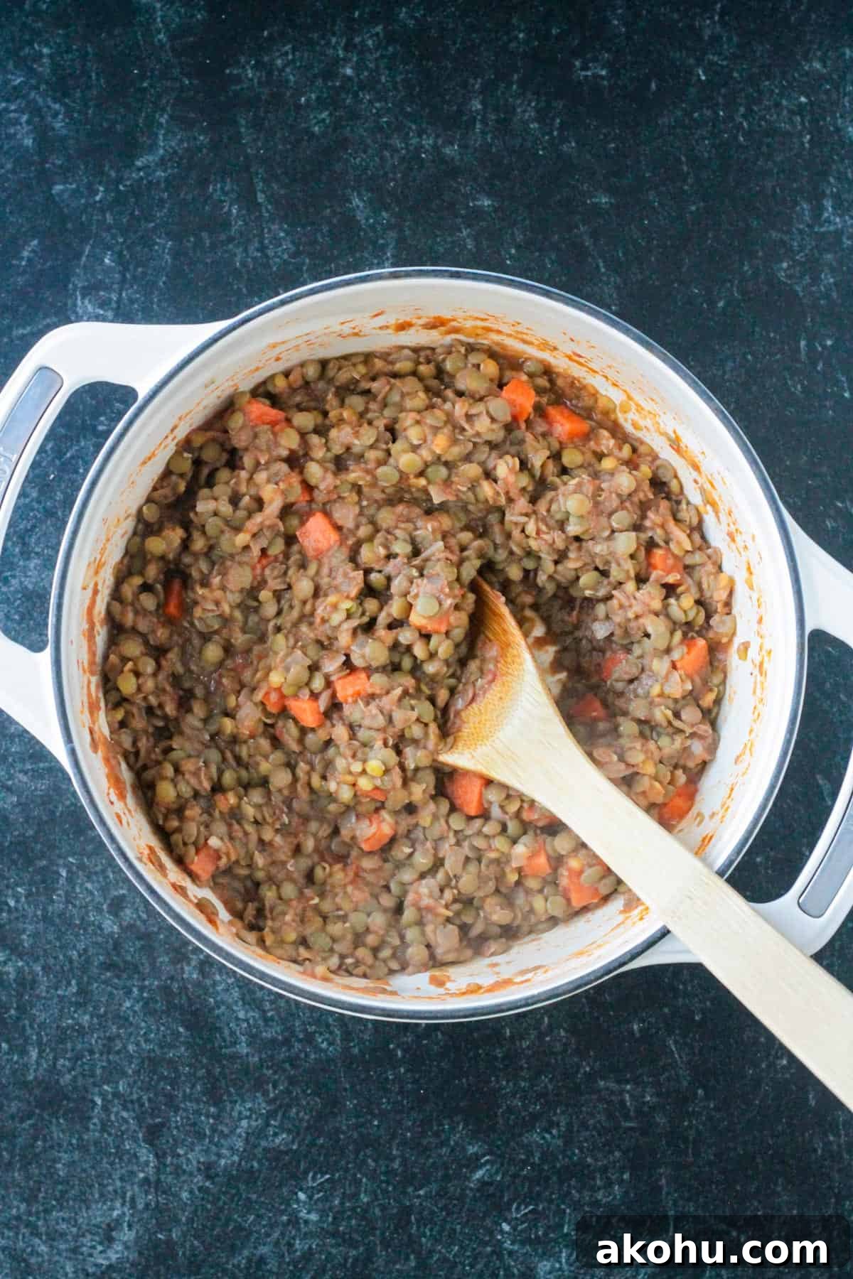 Cooked lentils mixed with spices and carrots in a pot.