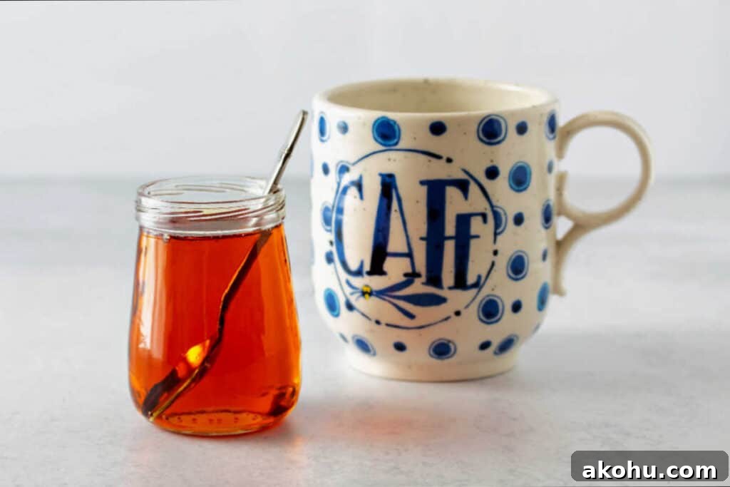 A horizontal image of a glass jar of caramel syrup and a coffee mug.