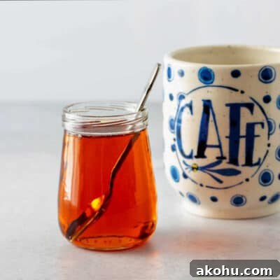 A square image of a small, clear glass jar of amber caramel syrup and a coffee cup.