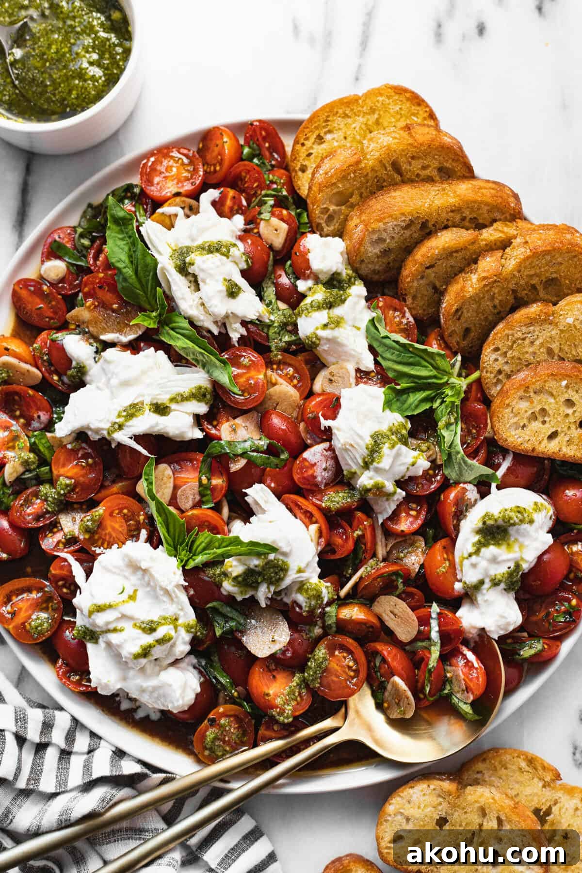 Large white plate with sliced tomatoes and burrata salad with crostini.