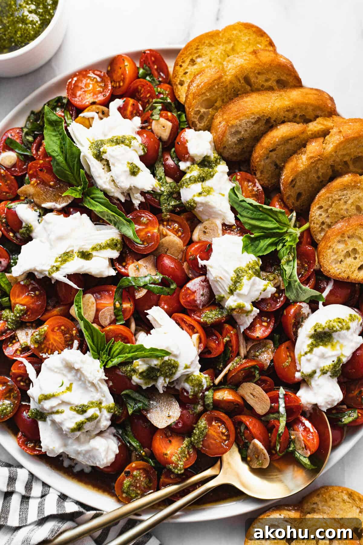 Large white plate with sliced tomatoes and burrata salad with crostini.