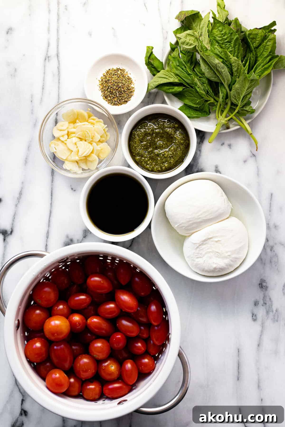 White marble counter top with ingredients to make tomato burrata salad.