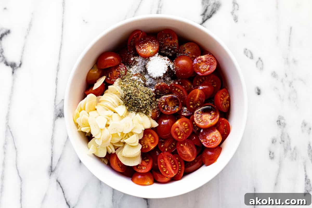 White bowl filled with sliced tomatoes, sliced garlic, and dried herbs.
