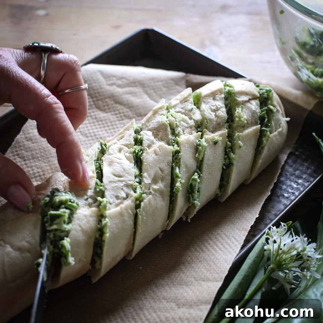 Womans hands spreading a small baguette with wild garlic butter