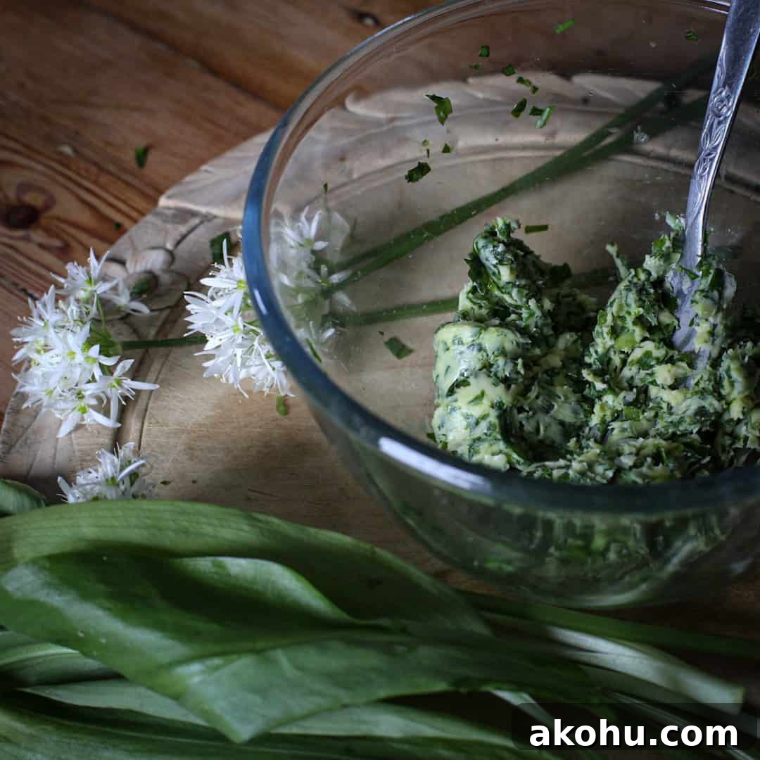 Glass bowl of wild garlic butter on a wooden counter with a bunch of wild ramsons
