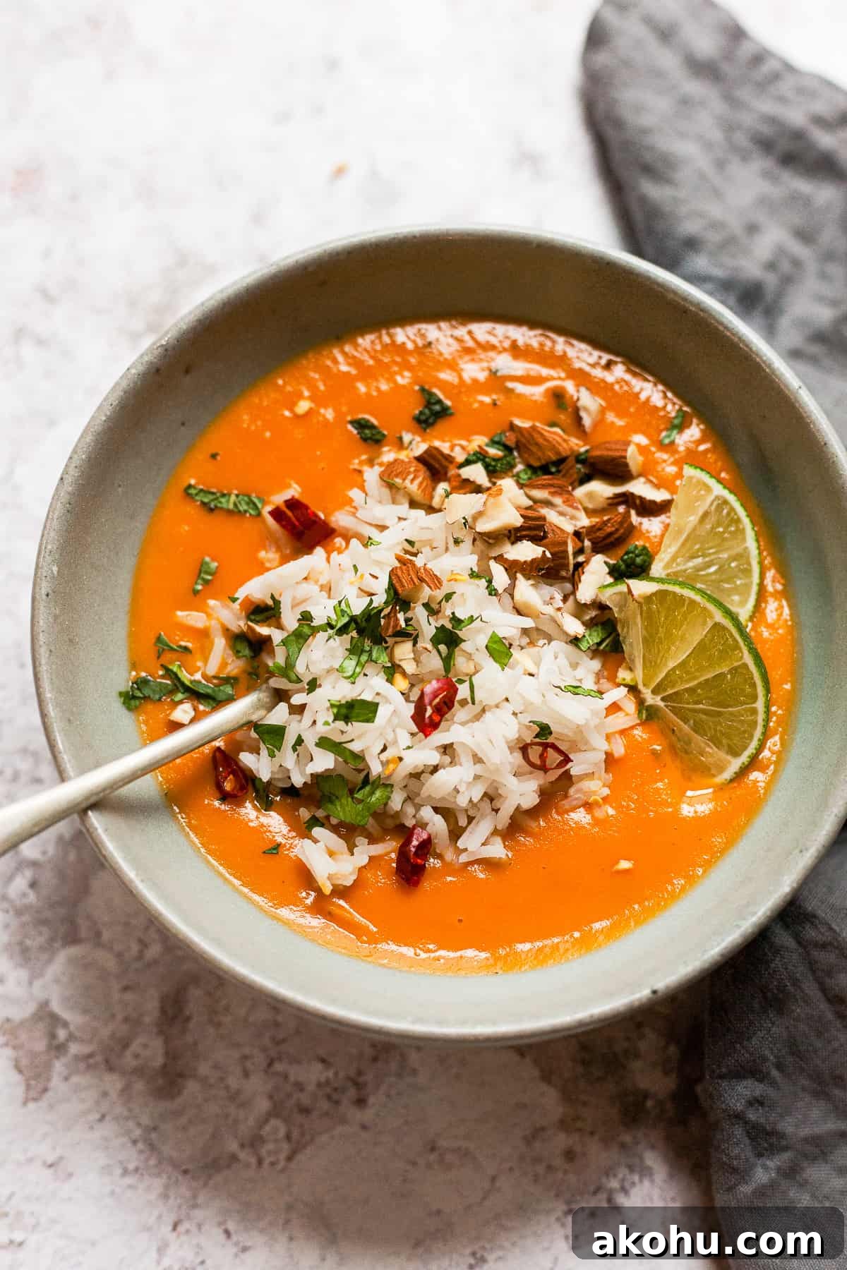sweet potato and carrot soup on a white table with a spoon and napkin.