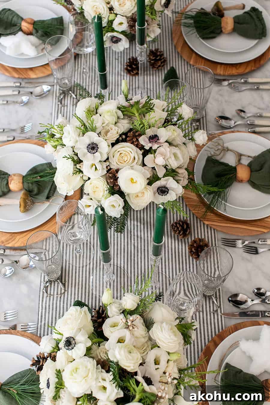 Christmas table decorations like flowers, candles, chargers and plates on a table.