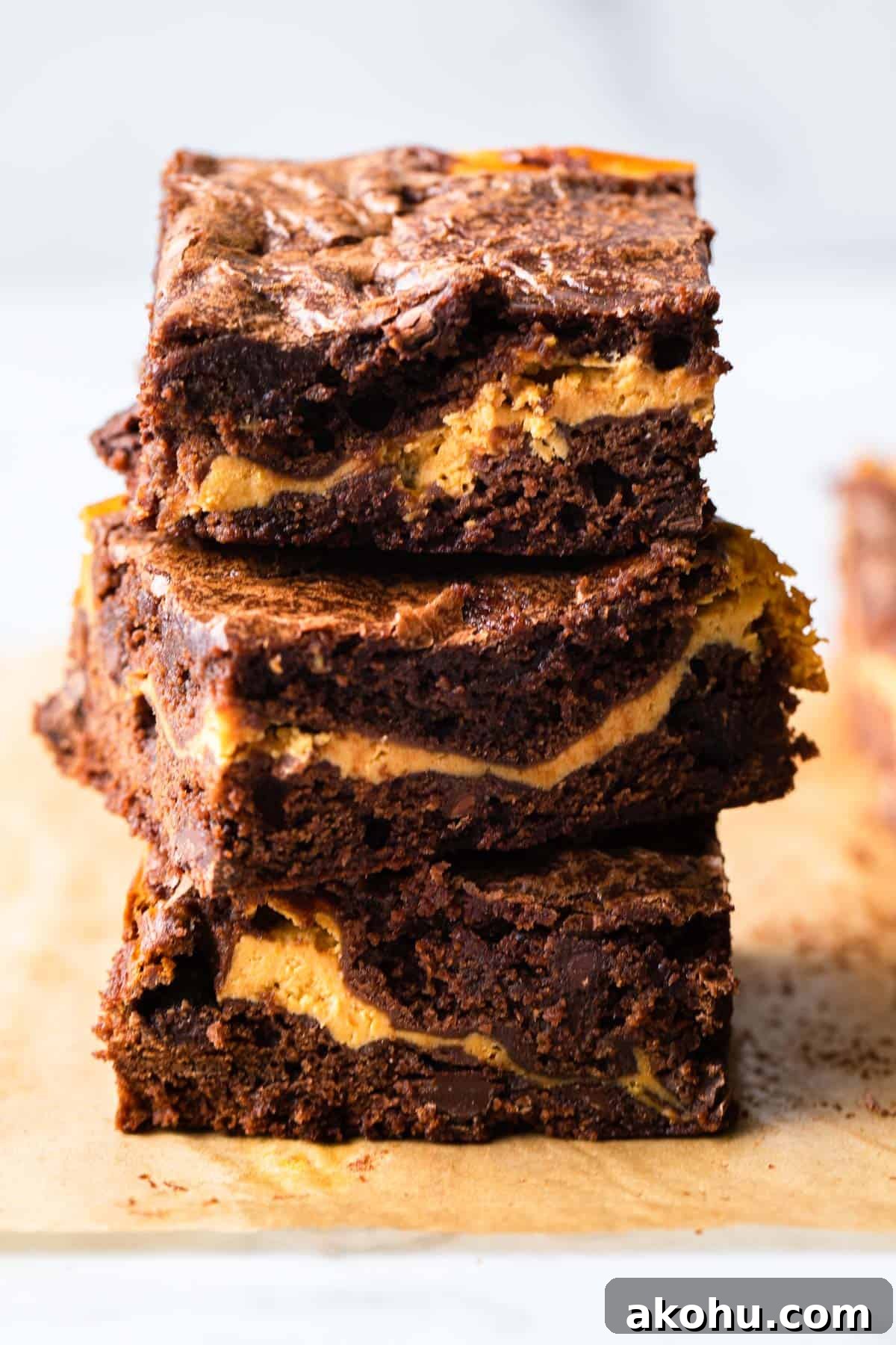 Pumpkin Swirl Cream Cheese Brownies Recipe 2 Stack of pumpkin brownies on parchment paper.