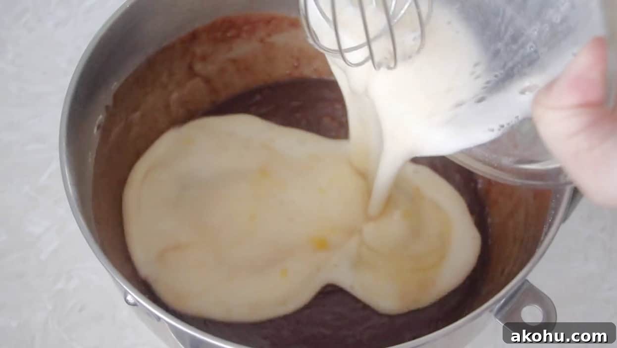 Ultimate Texas Sheet Cake Recipe for Rich Chocolate Dessert 8 Egg and milk mixture being poured over chocolate cake batter in bowl.